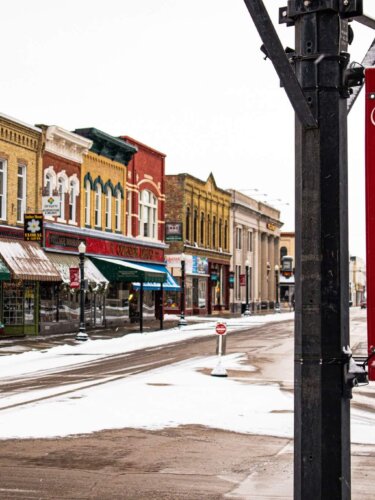 A snowy downtown street in Baraboo with a red Christmas banner on the light pole