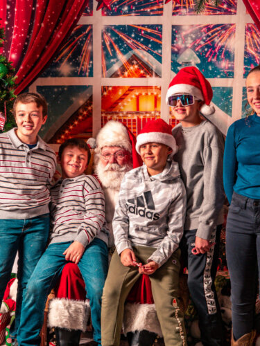 Five children meeting Santa, with festive holiday decor around them