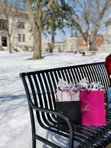 A mom and daughter sitting on a bench with shopping bags in Downtown Baraboo on a snowy day.