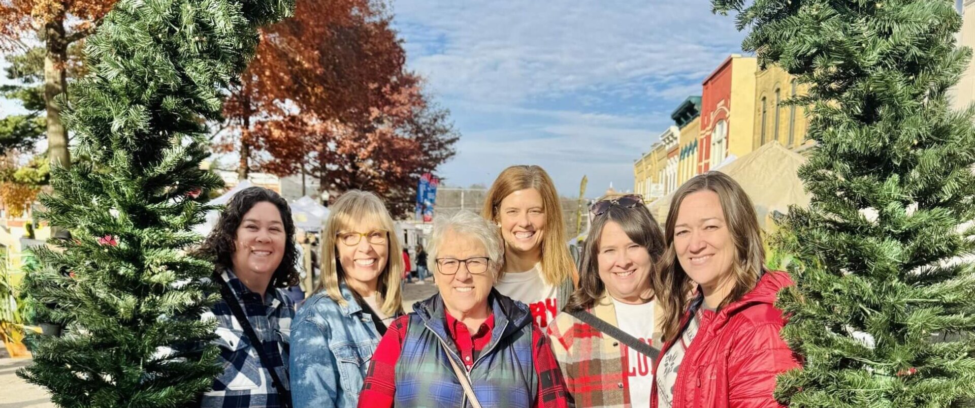 Six women shopping in Downtown Baraboo with a Christmas garland arch