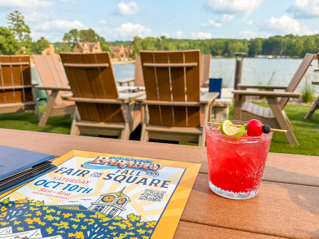 A cocktail at Daylene's Supper Club outside with the lakeview, along with a poster announcing the Baraboo Fall Fair on the Square