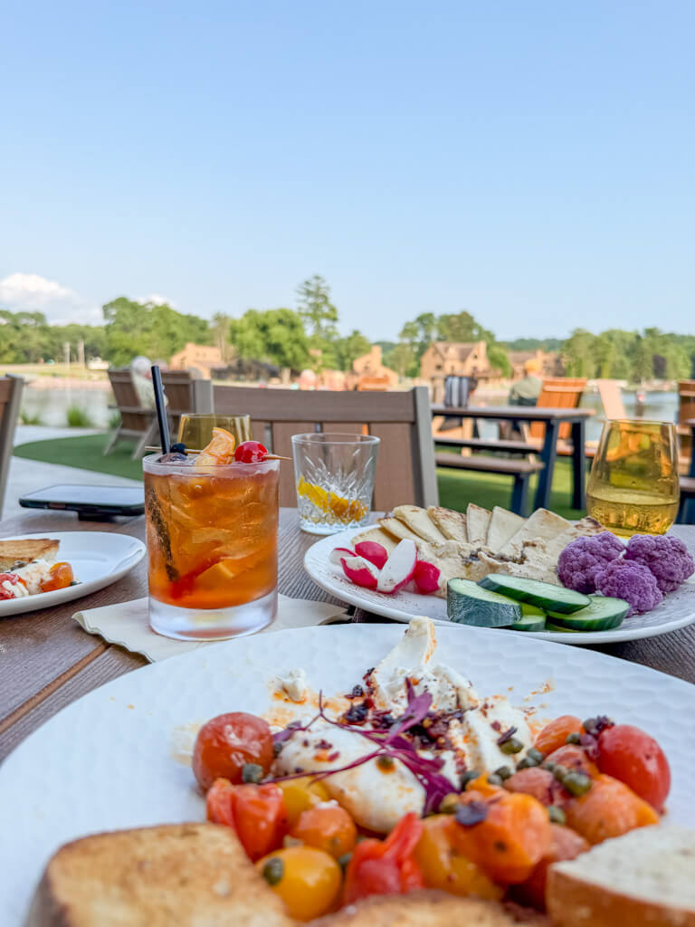 An old fashioned drink with garnish at a table at Daylene's on the shores of Lake Delton, along with tasty appetizers.