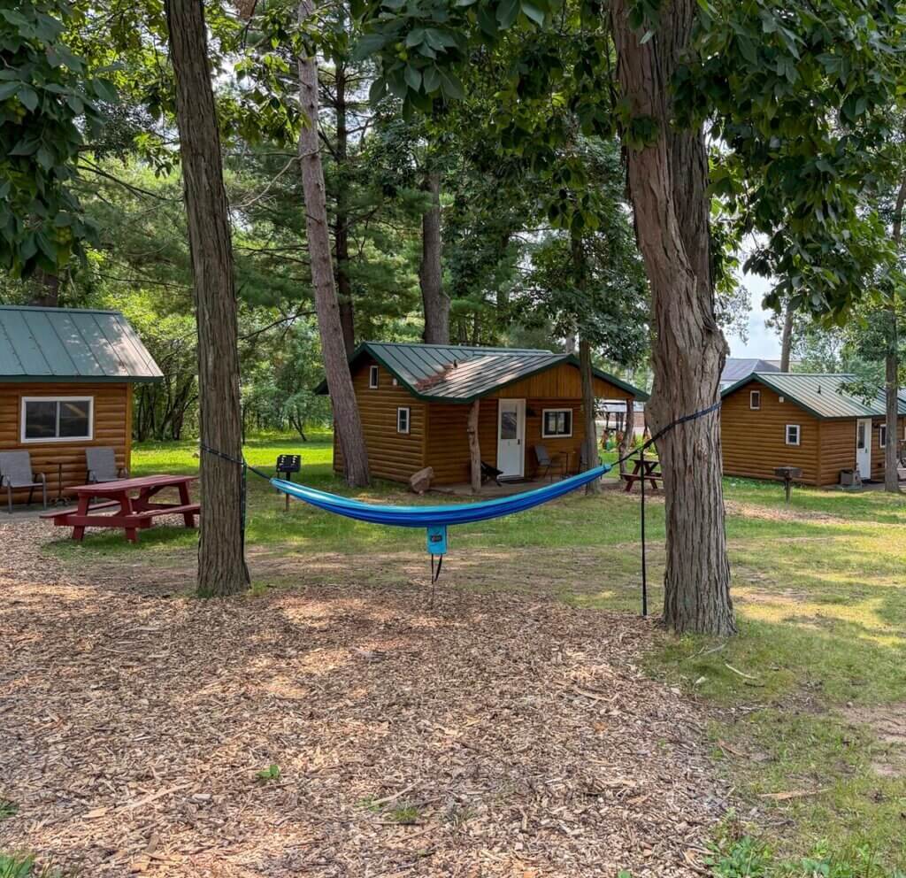 A view of Fireside Cabins in Baraboo, WI with cozy cabins and a hammock to lay in.