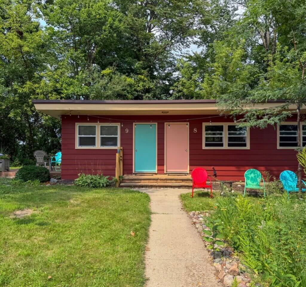 A view of Wildwood Inn in Baraboo, WI with pink and blue doors and a red motel.